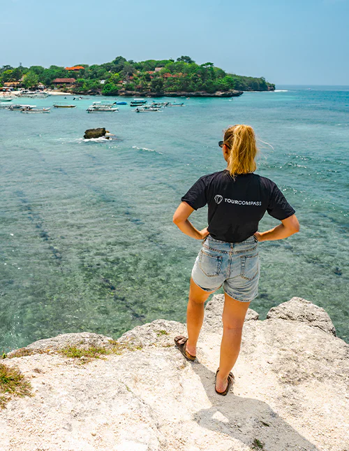 Woman wearing a TourCompass T-shirt enjoys the view over turquoise waters