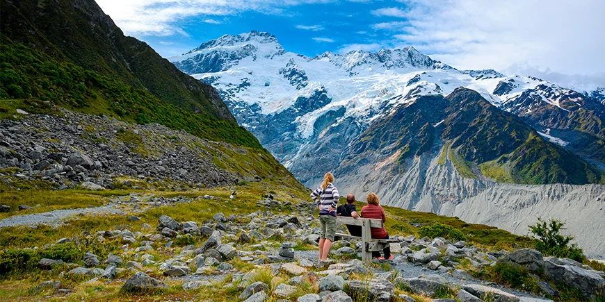 A family of three admires the mountains from the Kea Point viewpoint in Mount Cook National Park