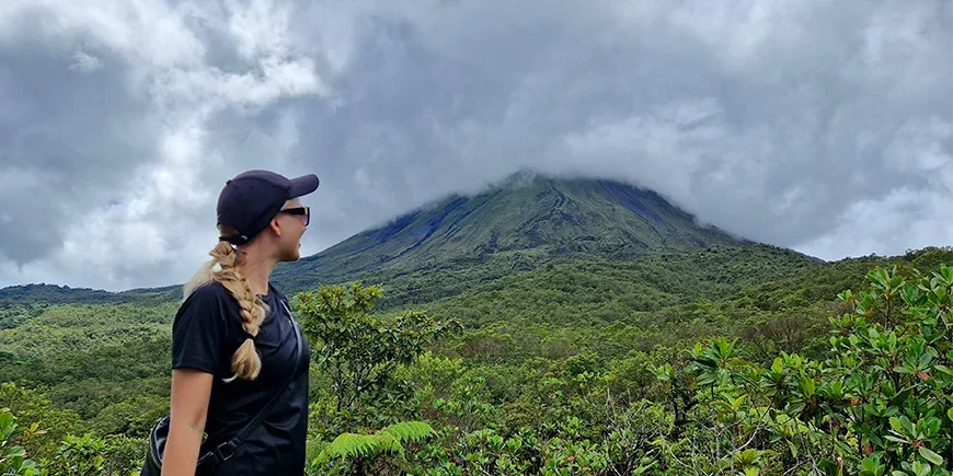 Nadia from TourCompass in front of Arenal Volcano on a cloudy day in Costa Rica