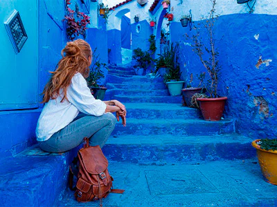 Woman sitting on stairs in the blue city of Chefchaouen, Morocco