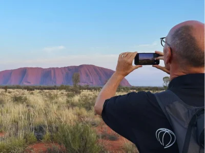 Man taking a photo of Uluru in Australia with his mobile phone