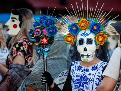 Woman dressed up with a skeleton face and flowers in her hair for Mexico’s Day of the Dead