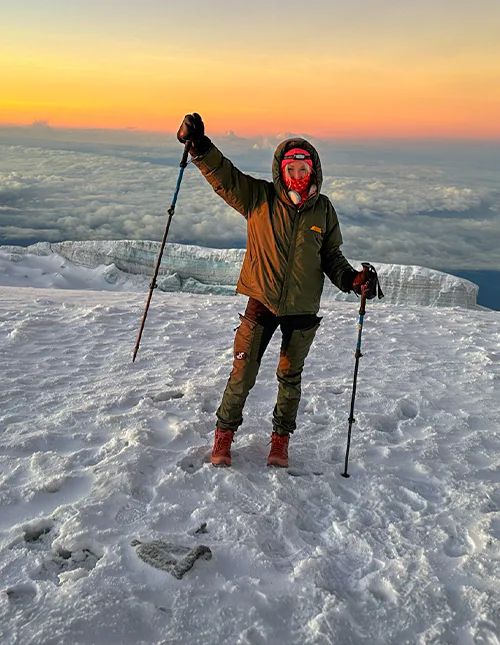 Cat from TourCompass stands at the summit of Kilimanjaro at sunrise