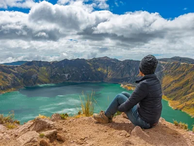 A woman sits on the rim of the Quilotoa crater lake in Ecuador.