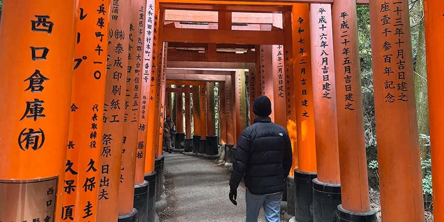 Man walking through the torii gates at Fushimi Inari