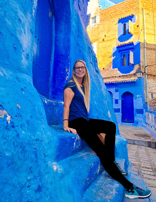 A woman sits on the steps in the blue city of Chefchaouen, Morocco
