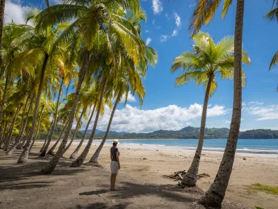 A woman stands on the beach at Playa Sámara, looking out at the water