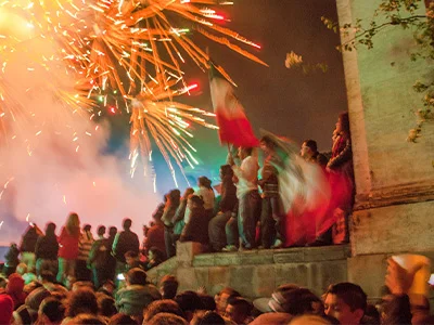 A large group of people celebrates Mexico’s Independence Day in a city centre with flags and fireworks