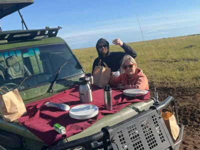 Two people having breakfast on the safari vehicle