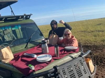 Two people having breakfast on the safari vehicle