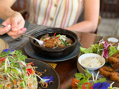 Visible woman’s hand reaching for food with a spoon in Vietnam