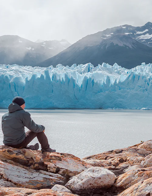 Man sitting in front of the Perito Moreno Glacier in Los Glaciares National Park