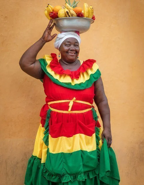 Smiling colombian lady holding a fruit bowl on her head