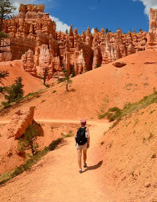 A person walks along a path among the iconic orange rock formations in Bryce Canyon National Park, Utah, USA.