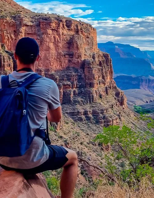 Man standing on a cliff along the Bright Angel Trail overlooking the South Rim in Grand Canyon National Park