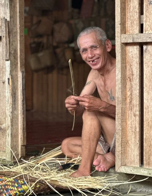 Smiling man weaving bamboo in the doorway